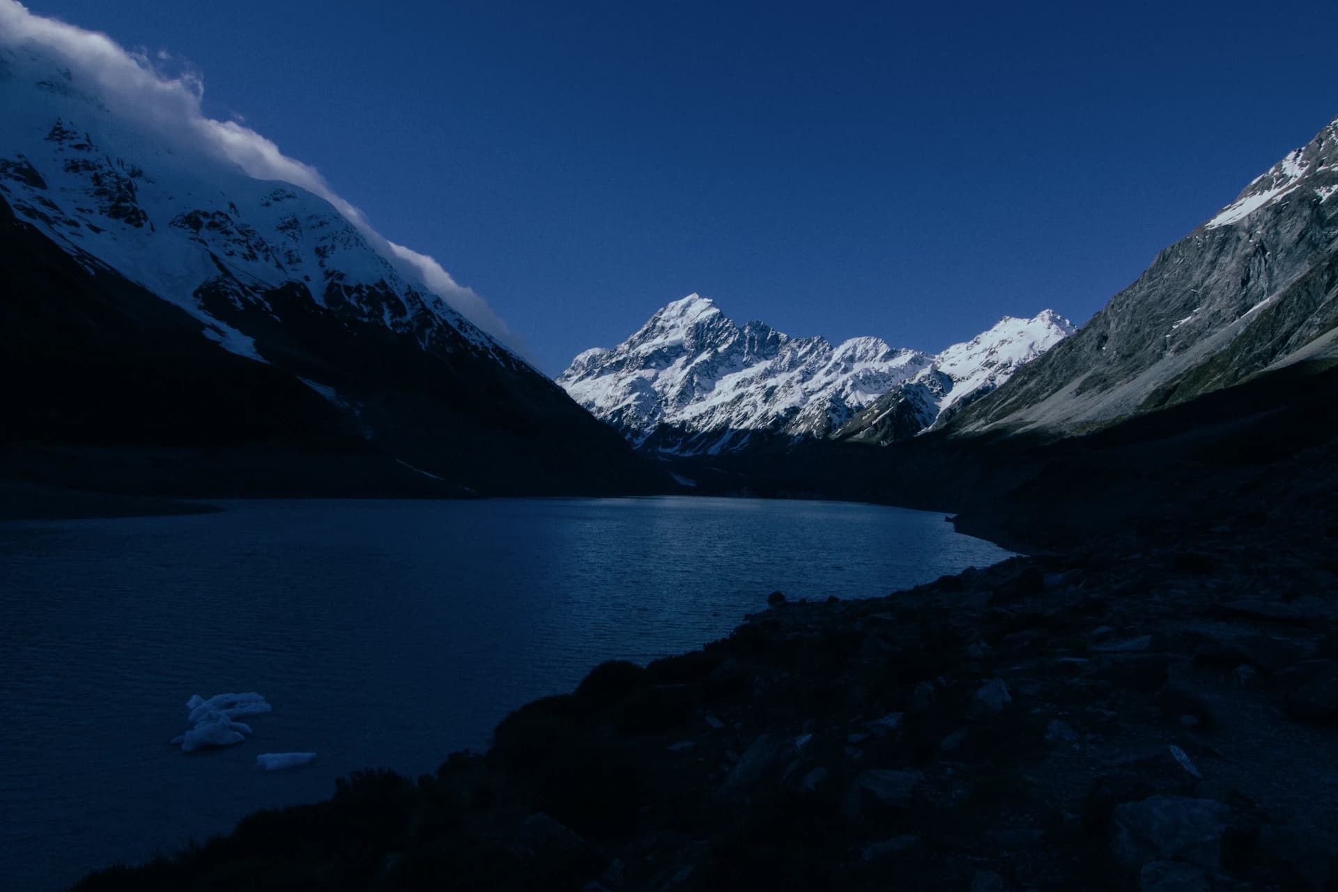 Snow-capped peaks at twilight above a still alpine lake — Southern Alps, New Zealand